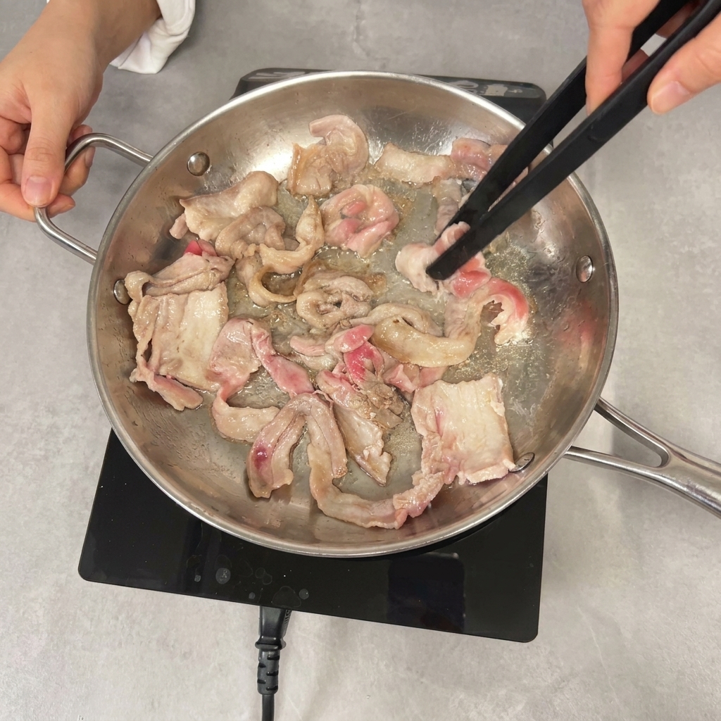 집게로 삼겹살을 볶으며 노릇하게 익히는 모습