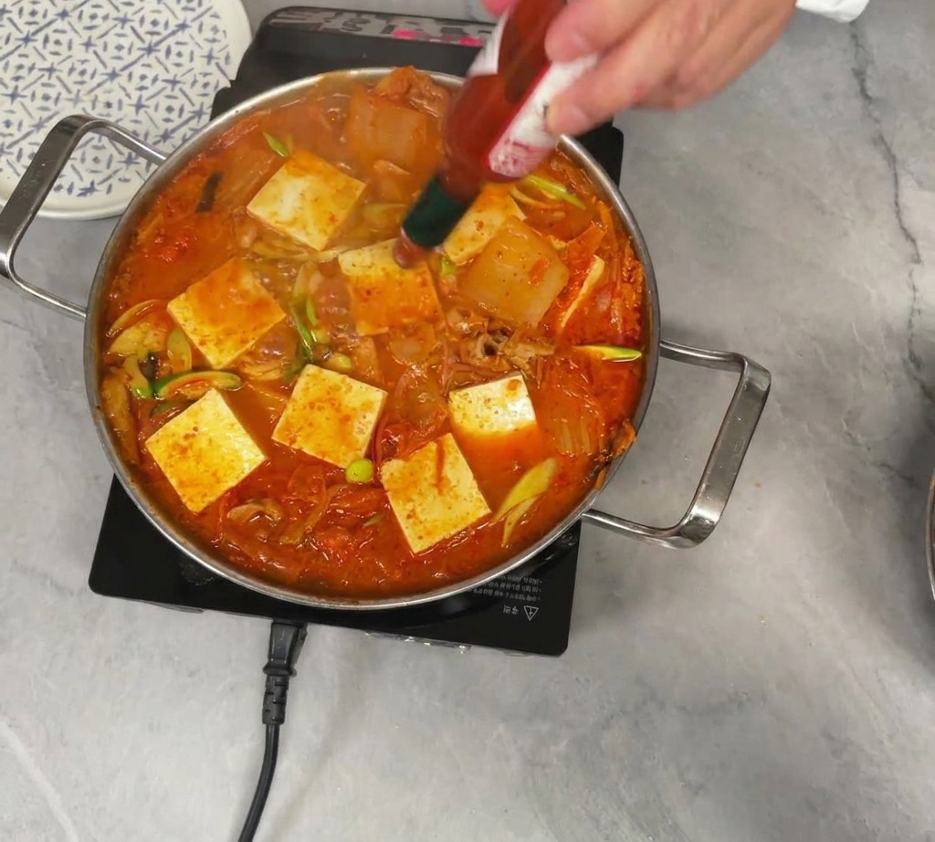 두부가 올려진 찌개에 타바스코 핫소스를 약간 뿌리는 모습