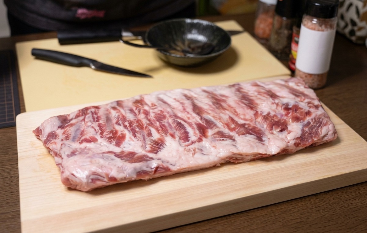 도마 위에 놓인 신선한 돼지갈비 한 대와 칼.