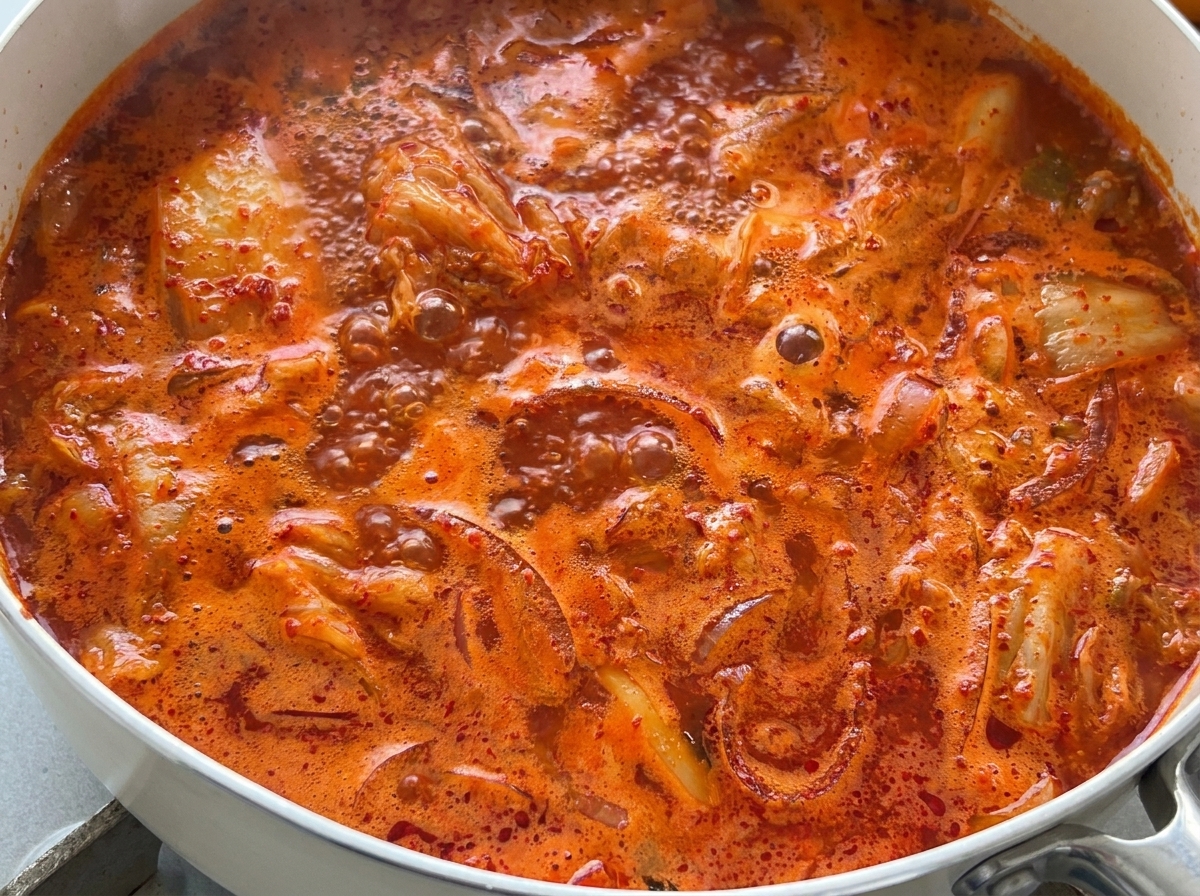팬에서 팔팔 끓고 있는 밝은 붉은색 김치찌개의 확대 모습.