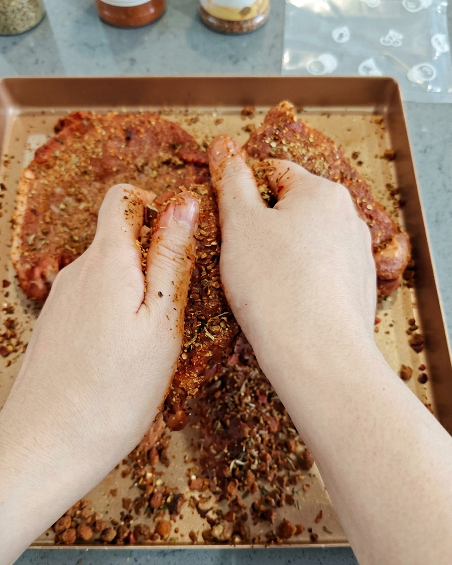 손으로 돼지고기 덩어리에 진한 양념 가루를 골고루 문지르는 모습
