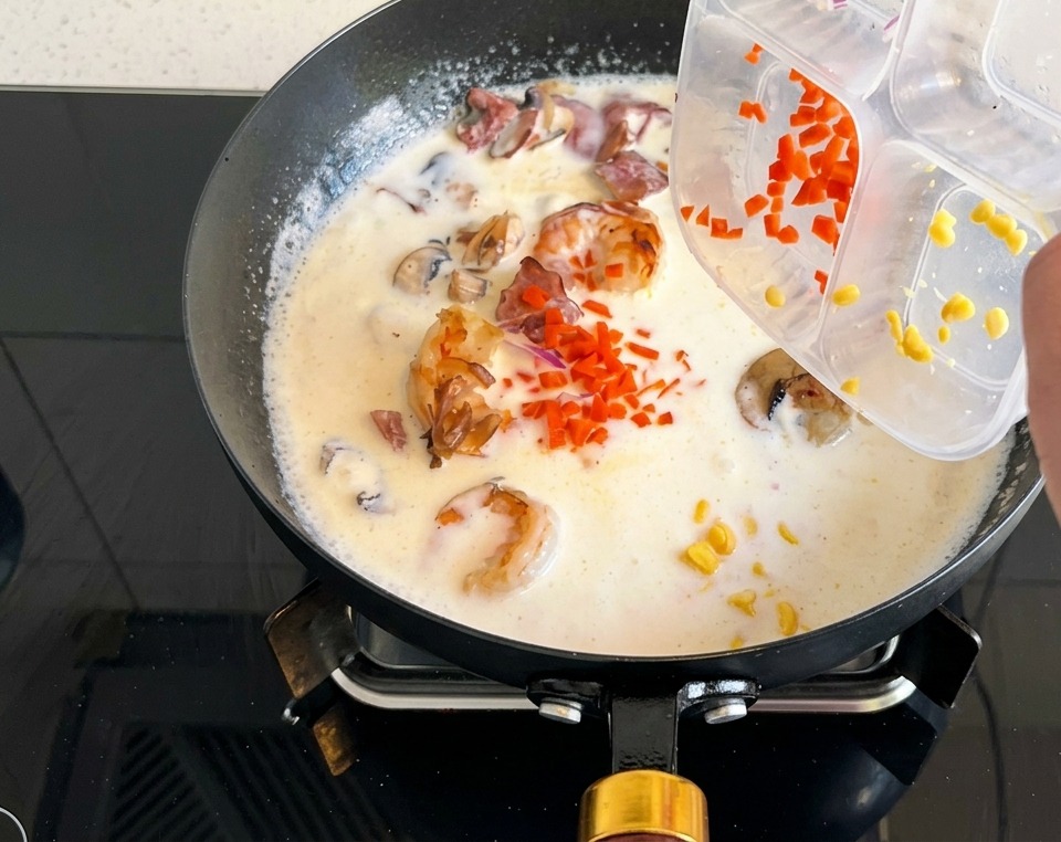 끓고 있는 크림스프에 다진 당근과 스위트콘을 넣는 과정.