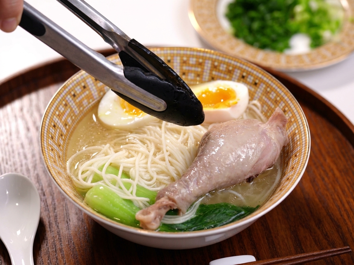 국수 그릇 위에 잘 익은 닭다리를 올리는 집게