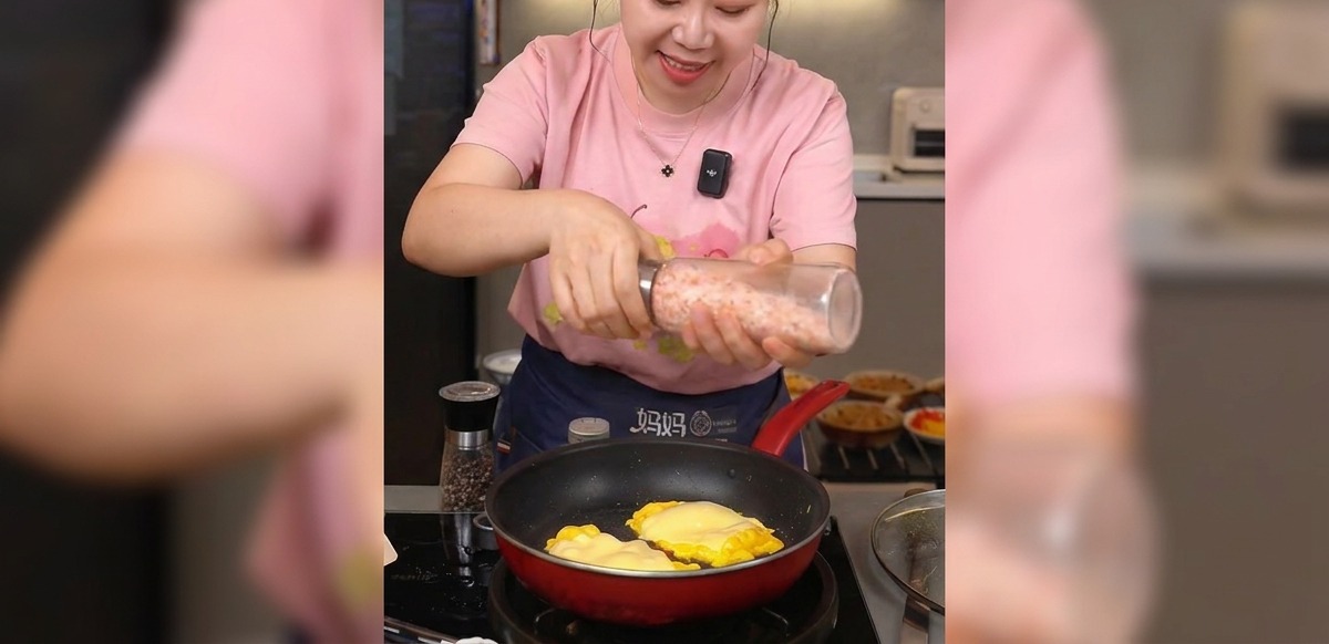 치즈가 녹은 계란 위에 핑크 솔트를 그라인더로 갈아 뿌리는 손.