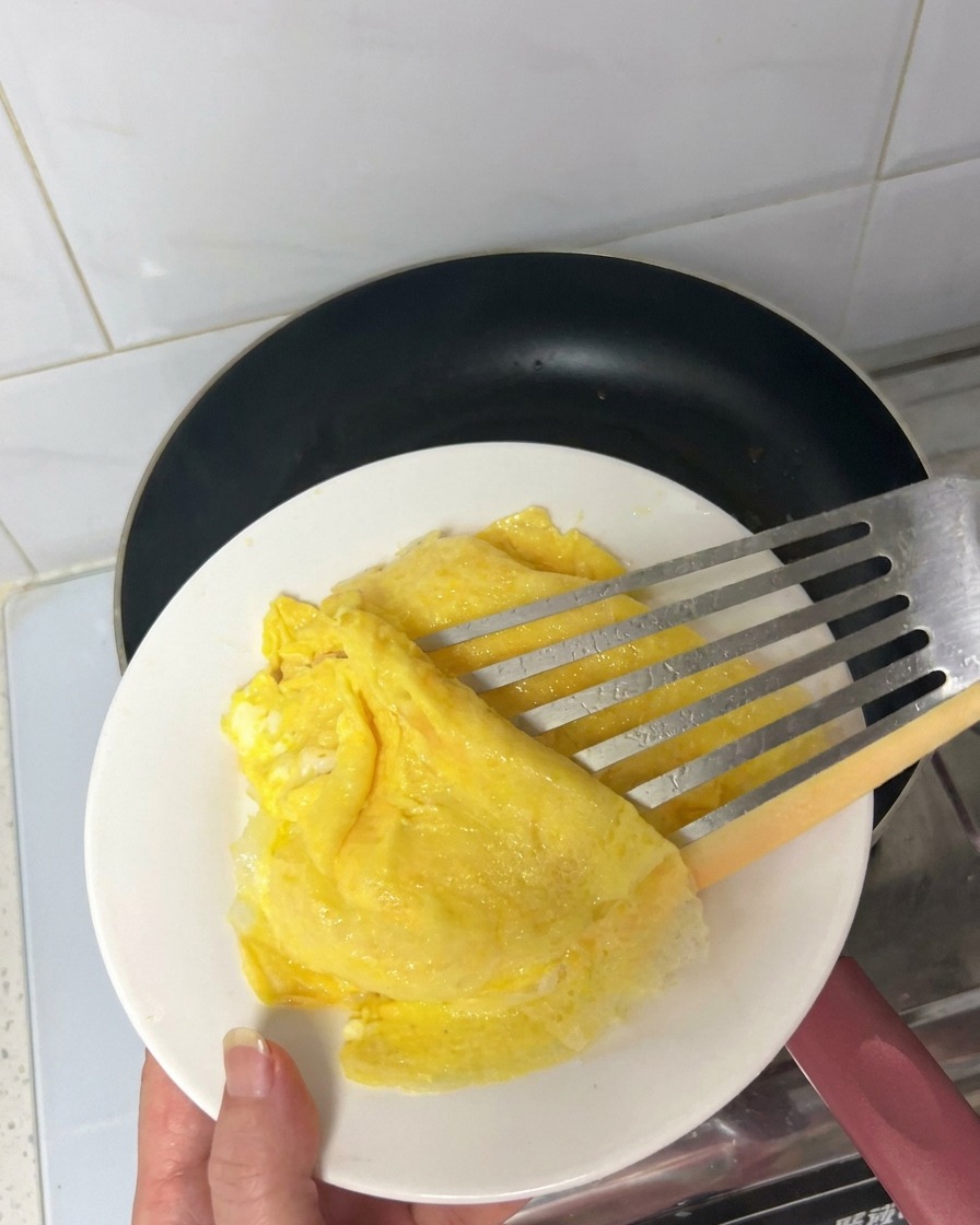 뜨거운 검은색 코팅 팬에서 베이컨이 구워지며 기름이 나오는 모습.