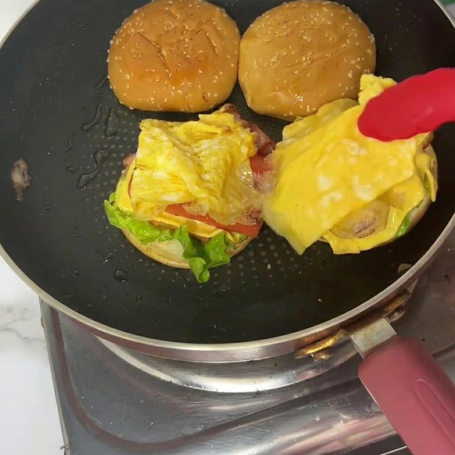 접시 위에 구운 참깨 번을 덮어 완성된 조식 버거의 모습.
