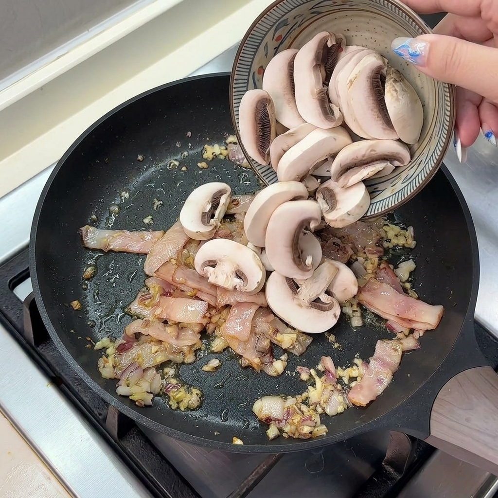 베이컨과 채소가 담긴 팬에 슬라이스한 양송이버섯 붓기