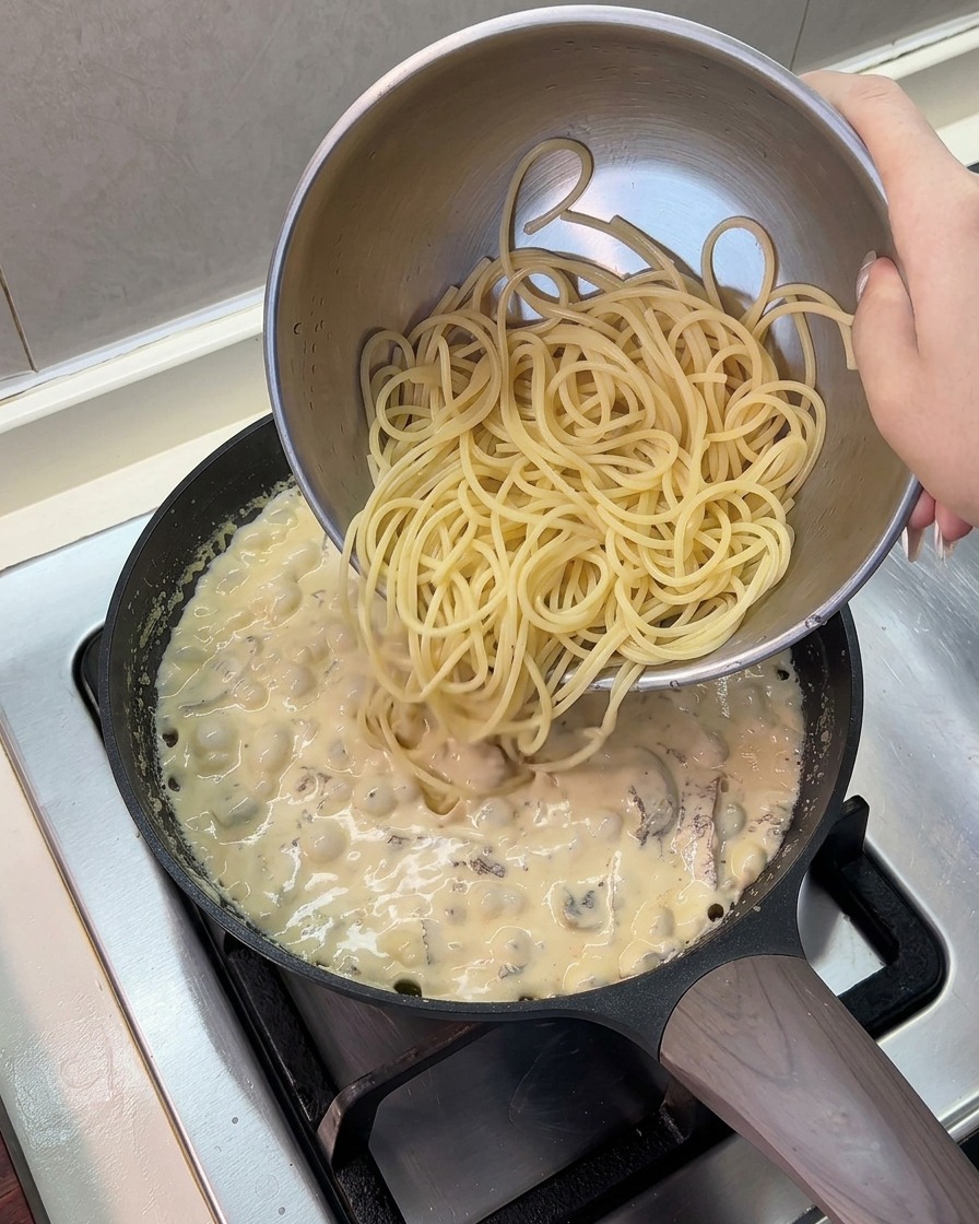 걸쭉해진 크림 소스에 삶은 스파게티 면 투하