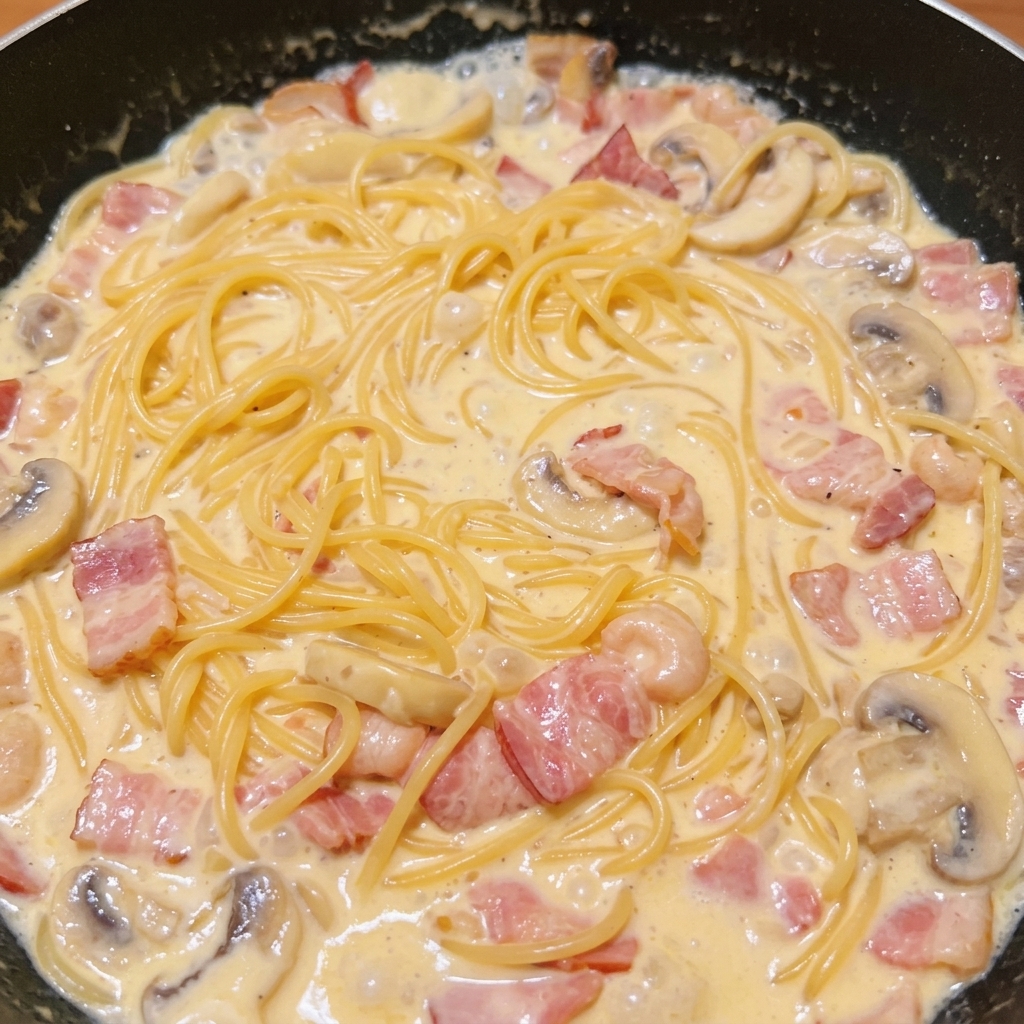 완성된 크림 소스에 삶은 스파게티 면을 넣고 섞는 모습.