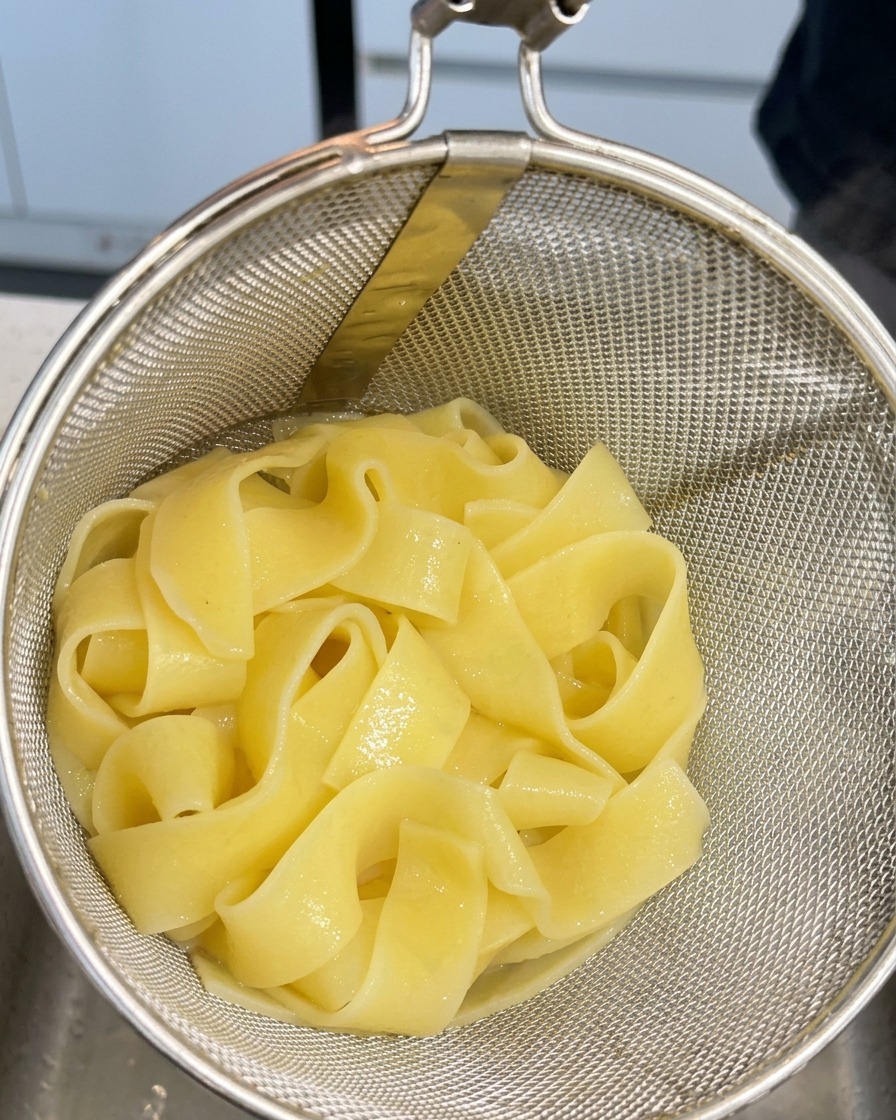 삶아진 파스타 면을 채반에 받쳐 물기를 빼는 모습.