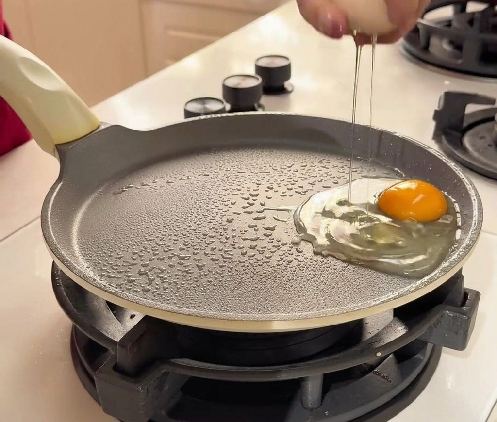 예열된 논스틱 팬에 두 개의 신선한 계란을 깨뜨려 넣는 모습.