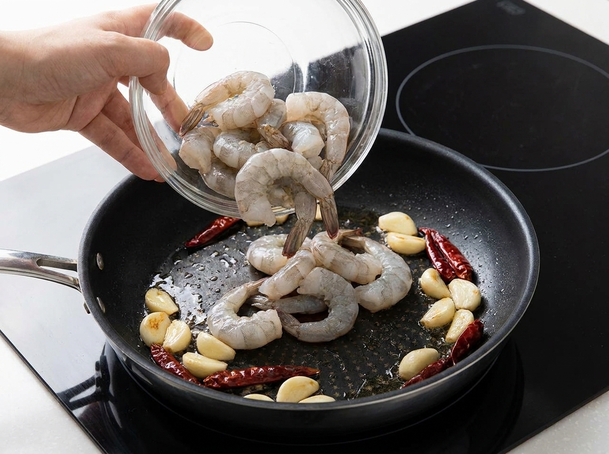 마늘과 건고추가 볶아지는 팬에 밑간한 새우를 넣는 과정.