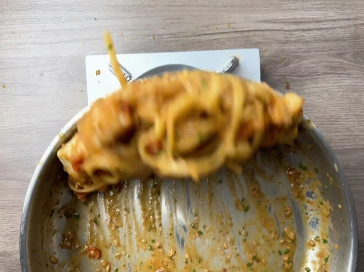 팬에서 생동감 있게 섞이고 있는 파스타와 새우.
