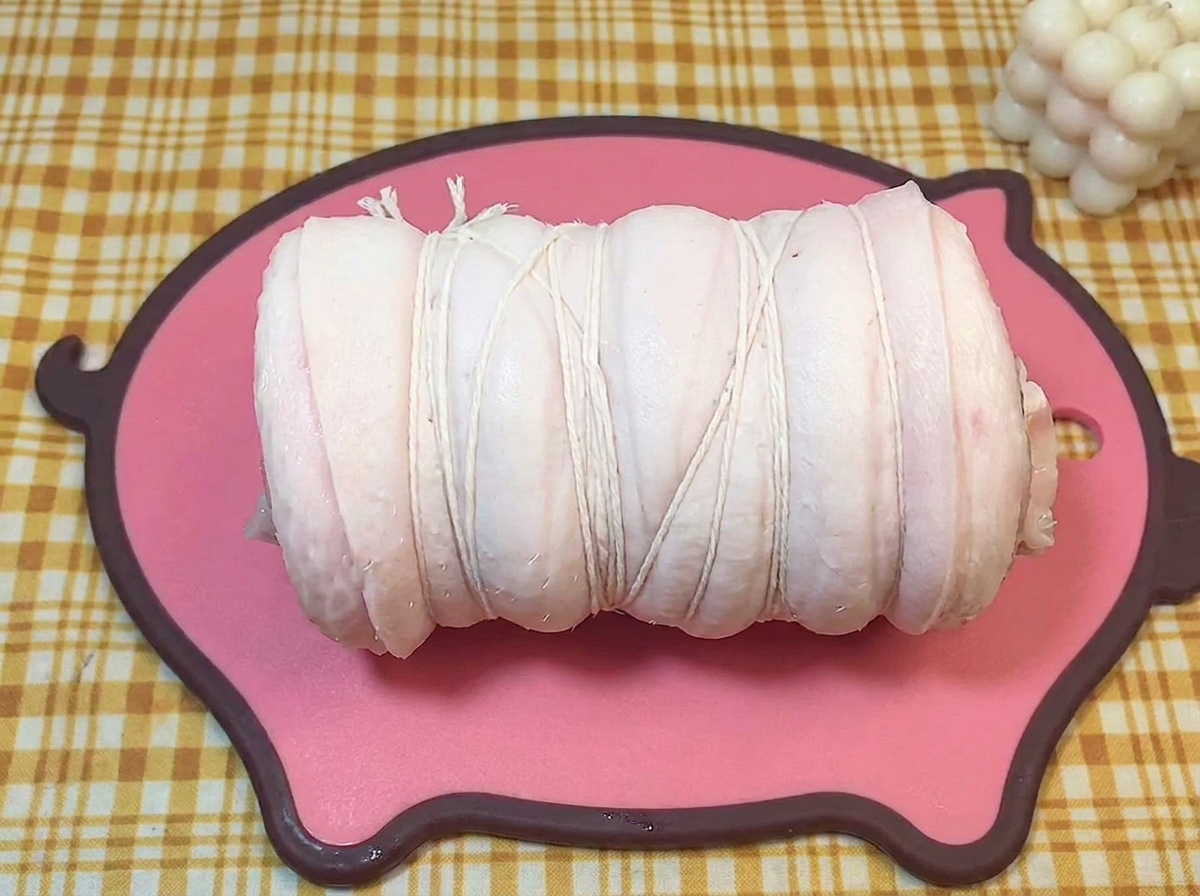 요리용 면사로 단단히 묶인 생삼겹살 롤.