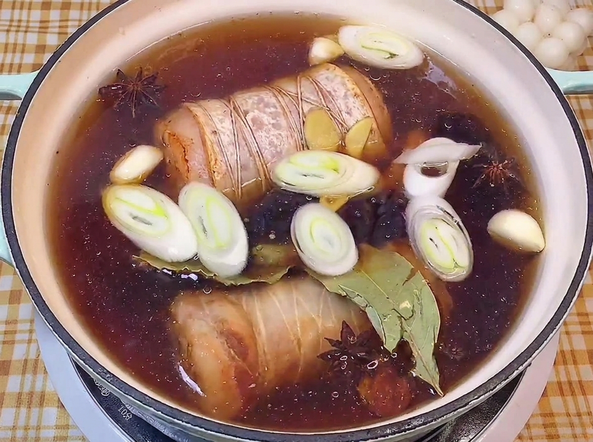 간장 베이스의 진한 국물에서 채소들과 함께 조려지고 있는 차슈 롤.