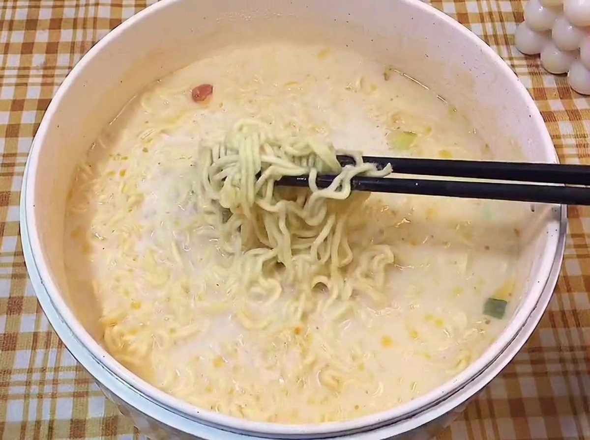 젓가락으로 탱글탱글한 라멘 면발을 들어 올리는 장면.