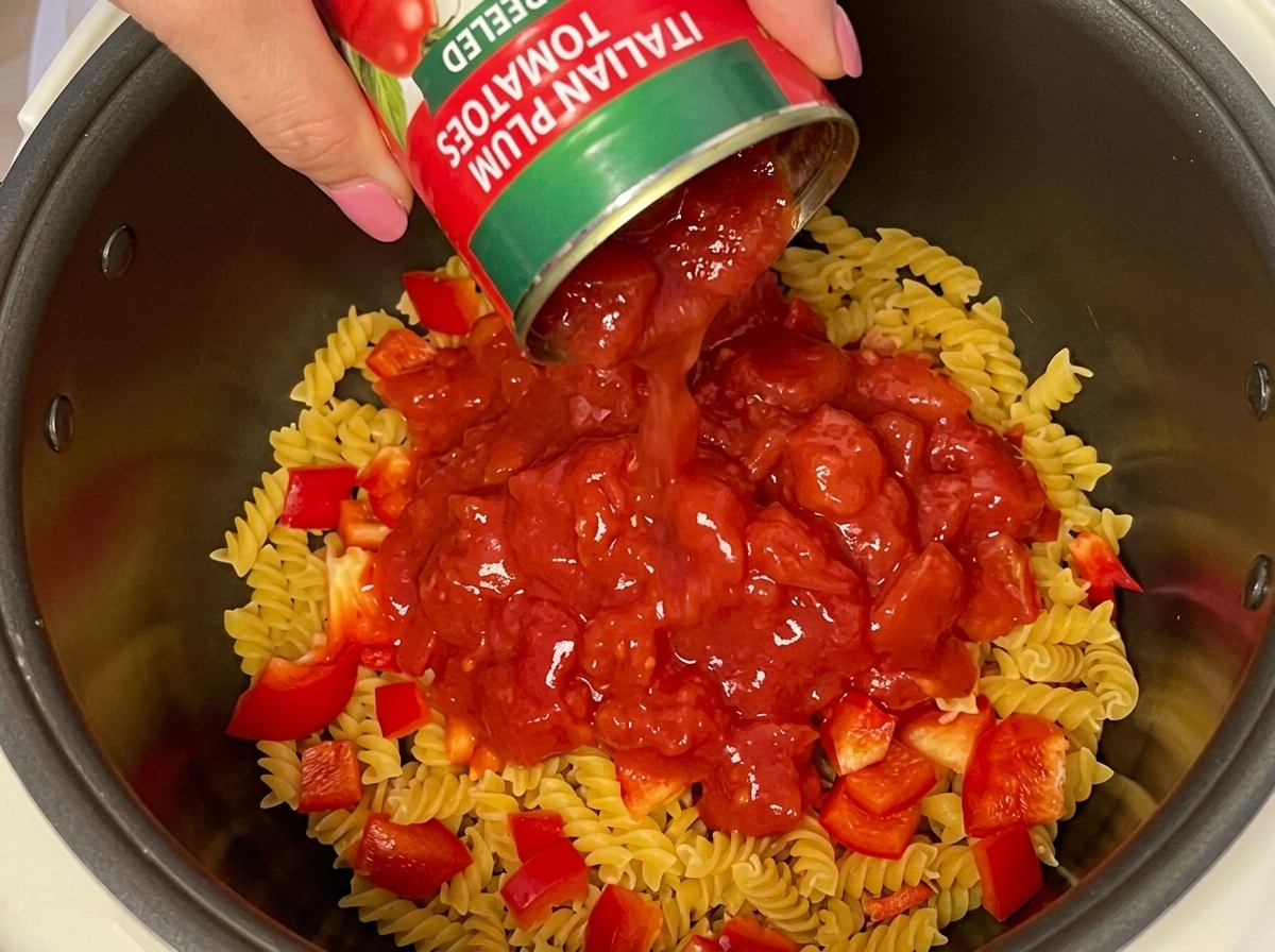 건푸실리와 파프리카 위에 다이스드 토마토 통조림을 붓고 있는 손.