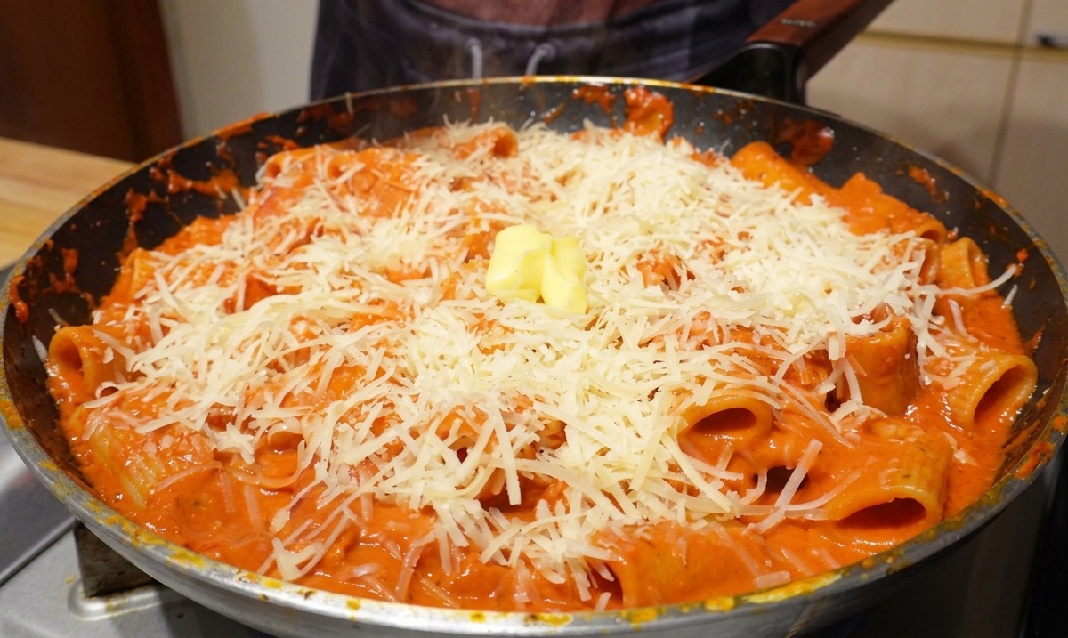 치즈가 뿌려진 파스타 중앙에 놓인 노란 버터 한 조각.