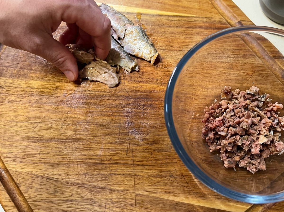도마 위에서 정강이 통조림의 가시를 제거하고 살을 바르는 모습.