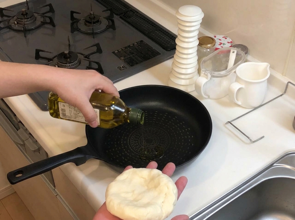 불을 켜지 않은 차가운 팬에 올리브 오일을 두르는 손과 다른 한 손에 들린 피자 반죽.