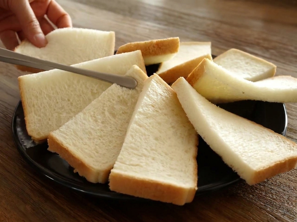 검은색 오븐 접시 위에 반으로 자른 식빵 조각들이 원형으로 겹쳐진 모습.