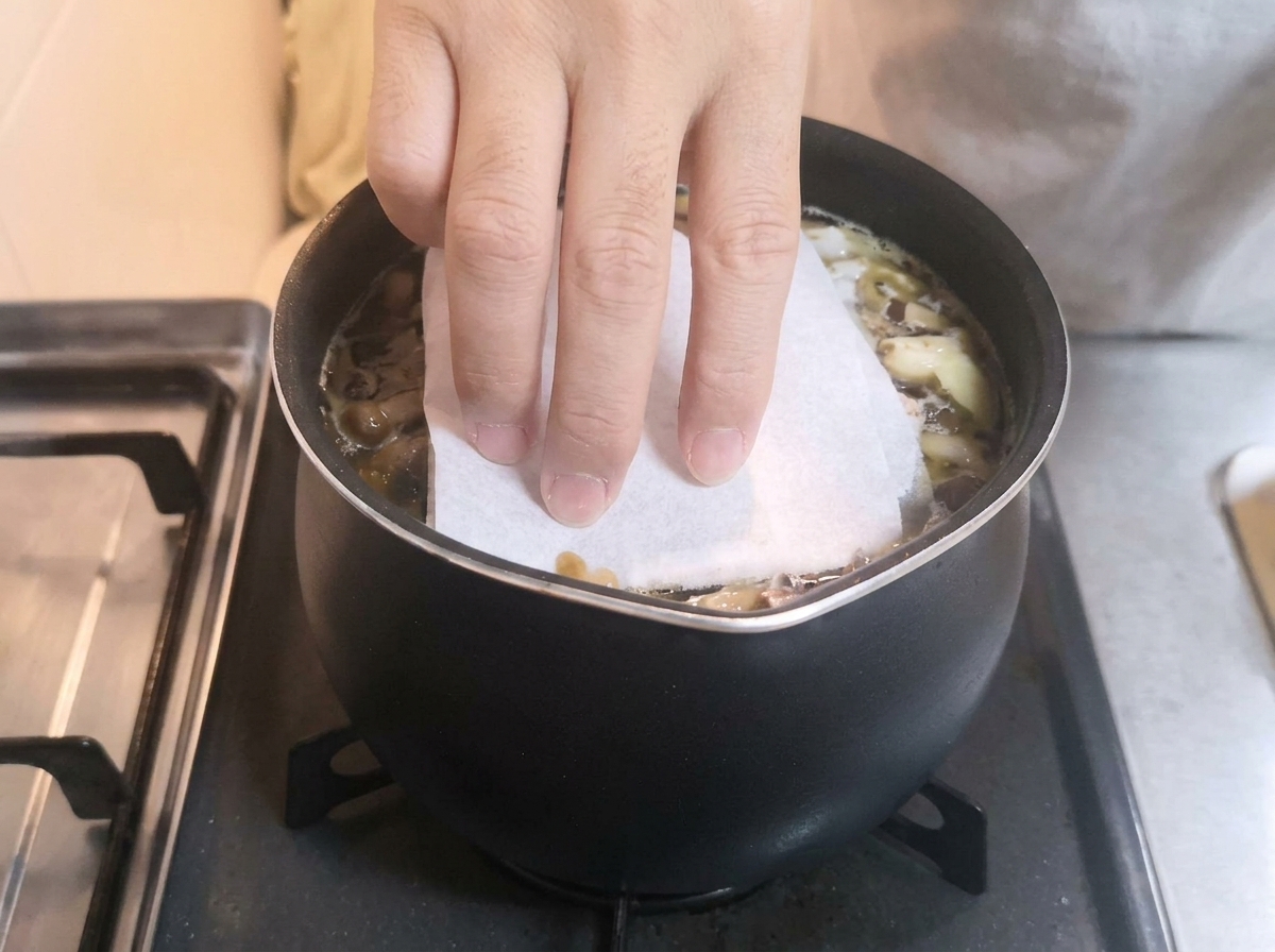 조림장이 끓는 냄비 위를 다시 종이 타월로 덮는 모습