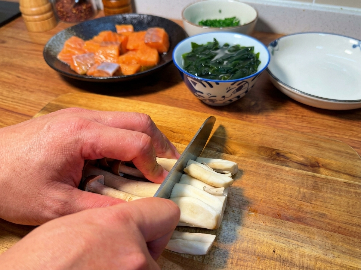 도마 위에서 만가닥버섯의 밑동을 칼로 잘라내는 손.