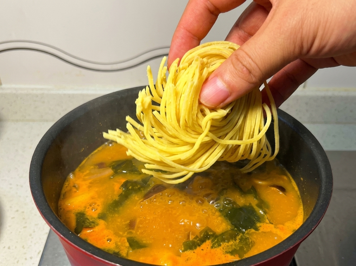 끓는 국물 속에 생라멘 면을 넣고 골고루 익히는 모습.