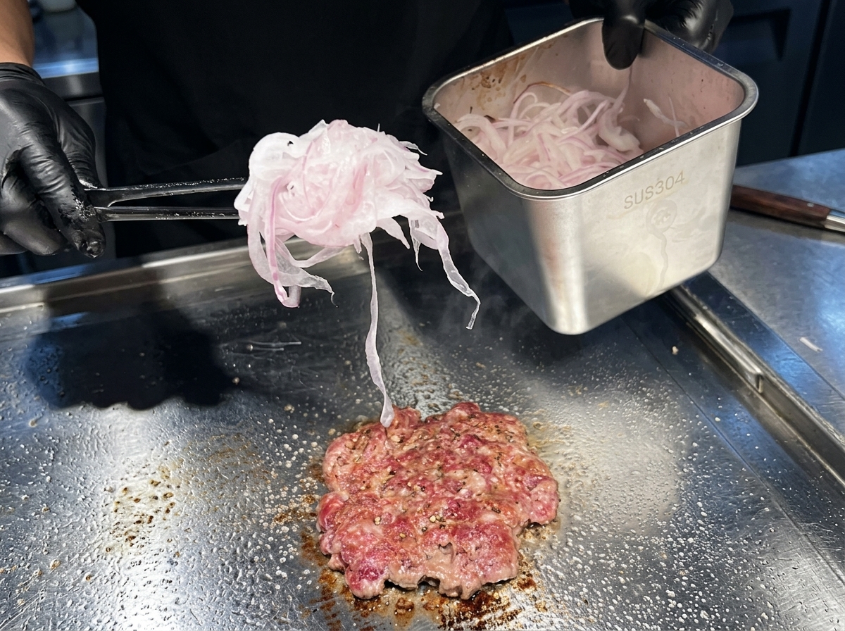익어가는 고기 패티 위에 아주 얇게 채 썬 적양파를 듬뿍 올리는 모습.
