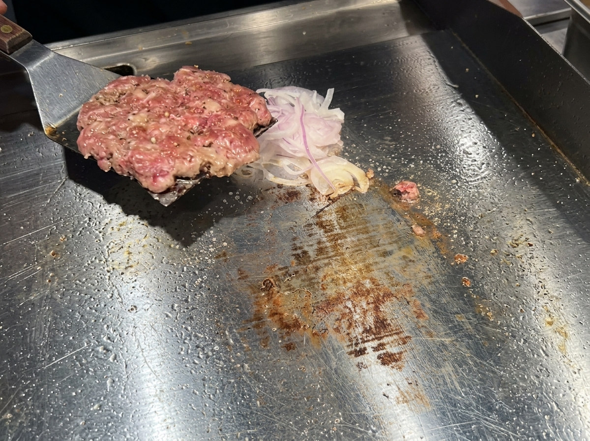 뒤집개를 사용해 갈색으로 잘 익은 패티를 뒤집어 양파가 바닥으로 가게 하는 모습.