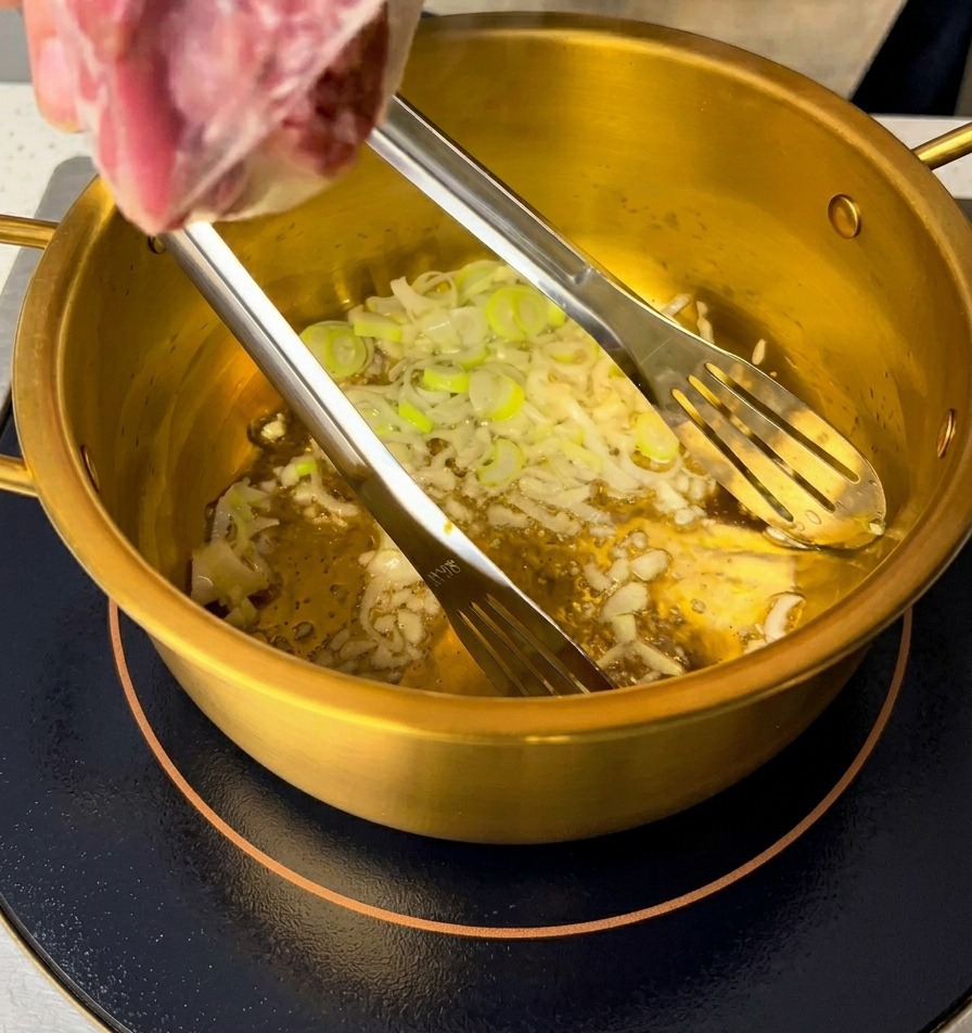 냄비 바닥에서 기름과 함께 볶아지고 있는 쪽파와 다진 마늘.