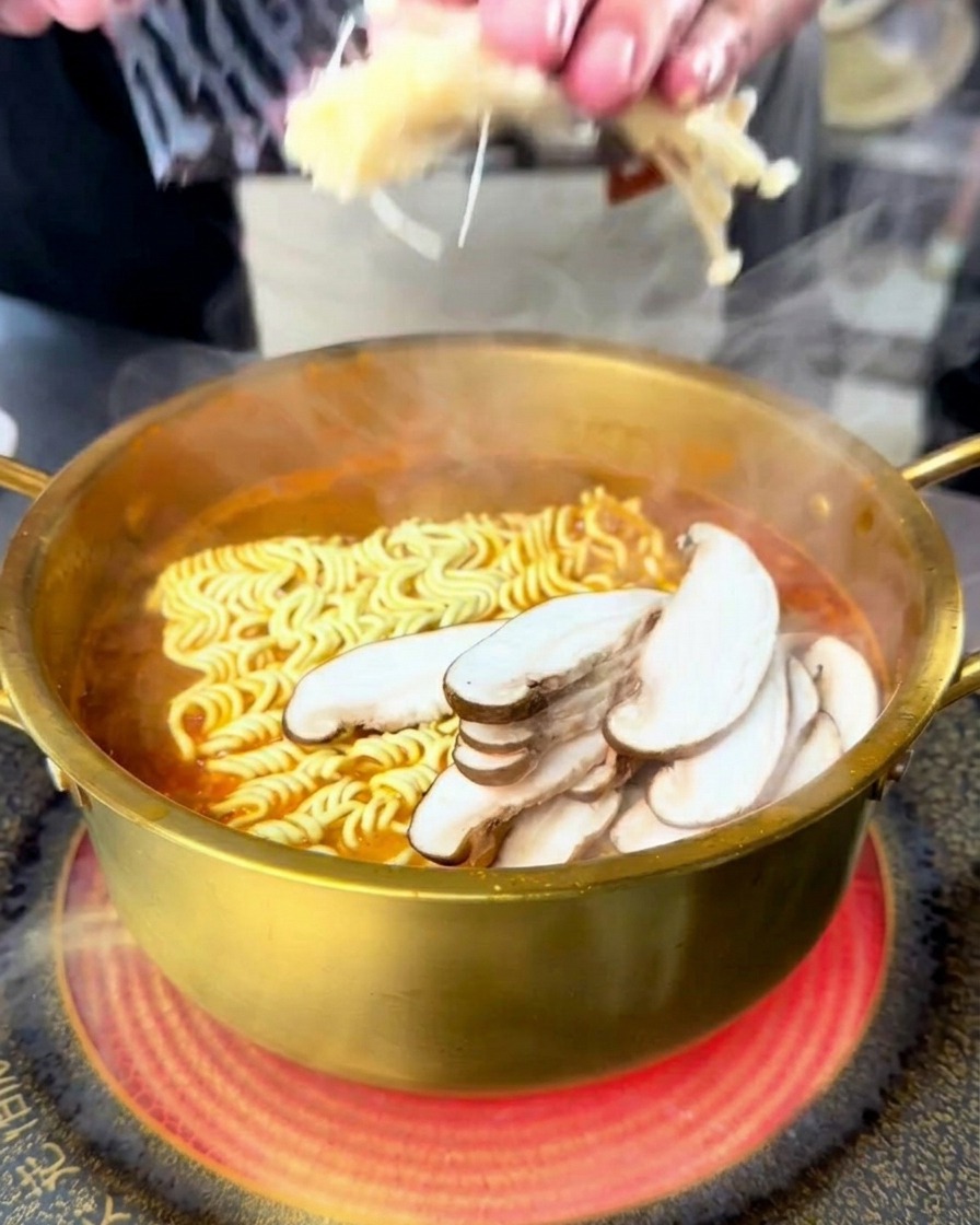 끓는 해물 라면에 팽이버섯과 표고버섯을 올리는 모습.