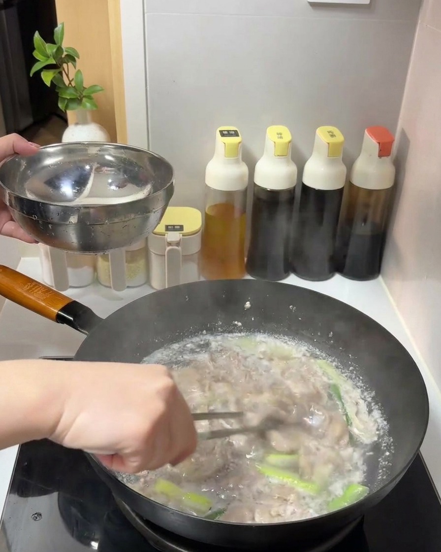 보글보글 끓는 물에서 집게를 이용해 잘 익은 소고기 슬라이스를 건져 스테인리스 볼에 담는 모습.