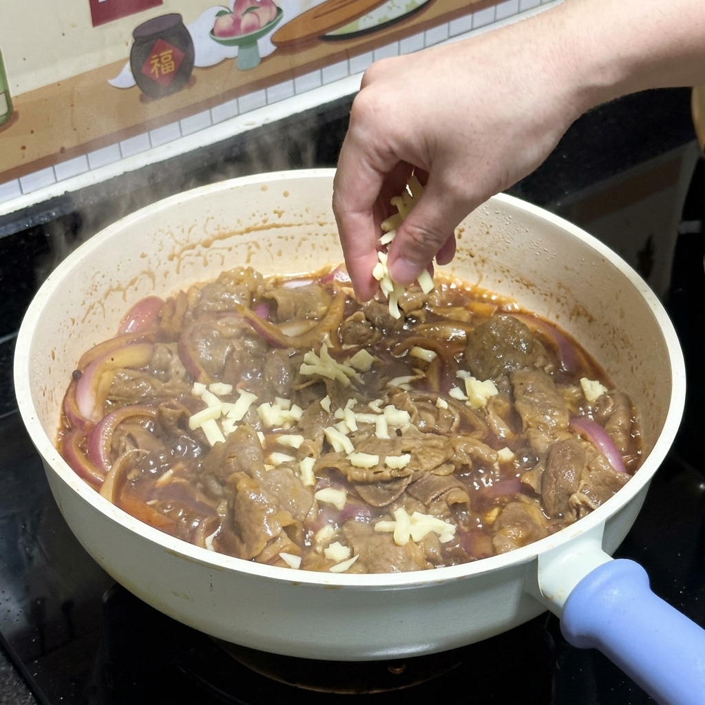 프라이팬 속 맛있게 익은 데리야끼 소고기와 적양파 위로 모짜렐라 치즈 가루를 듬뿍 뿌리는 모습.