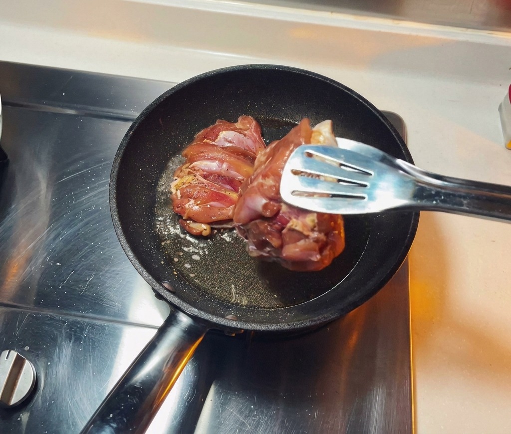 기름을 두르고 달군 프라이팬에 밑간한 닭다리살의 껍질이 아래로 향하도록 올리는 모습.