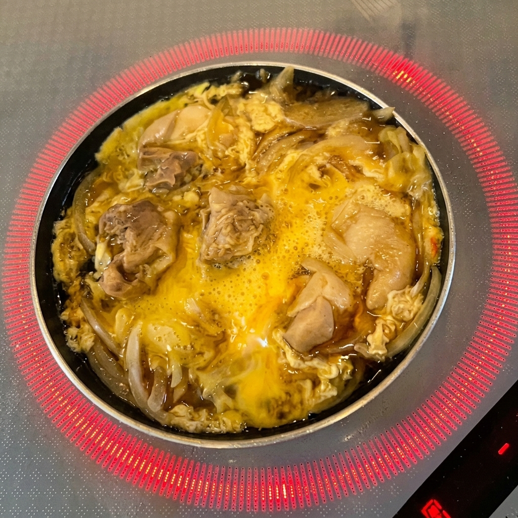 살짝 익어가는 달걀과 닭고기 위에 신선한 초록색 참나물 잎을 올리는 모습.