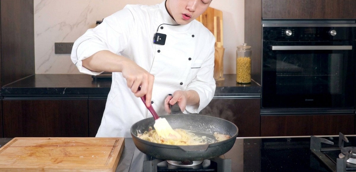 스패출러를 이용해 팬 안의 소스가 면에 고루 묻도록 정성껏 섞는 모습.