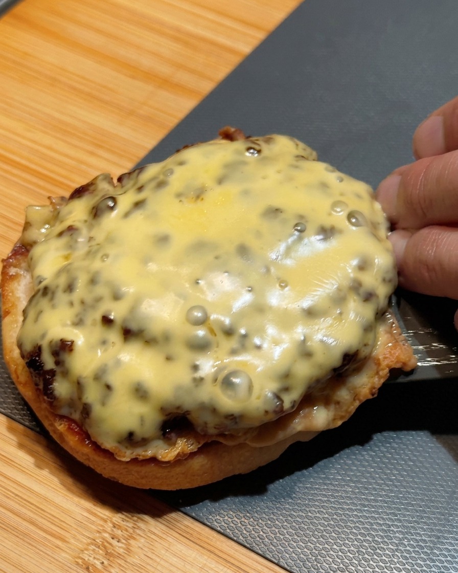 치즈가 녹은 두 개의 패티를 겹쳐서 번 위에 올리는 모습.