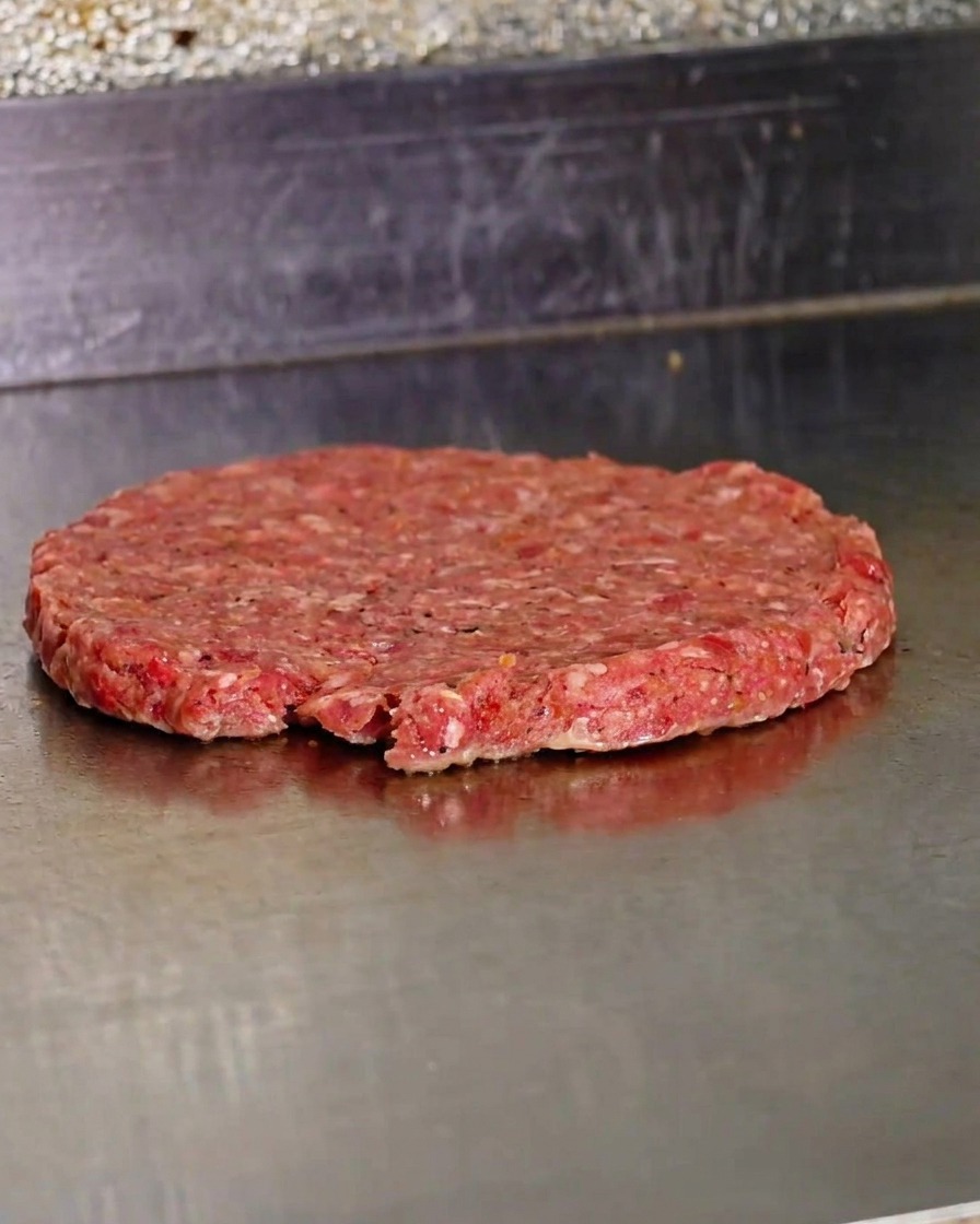 뜨거운 그리들 위에서 얇게 펴진 생소고기 패티의 모습.