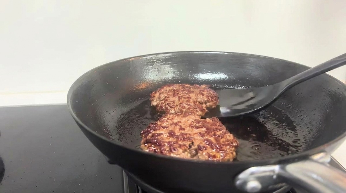 뒤집개로 노릇하게 구워진 패티를 뒤집는 모습
