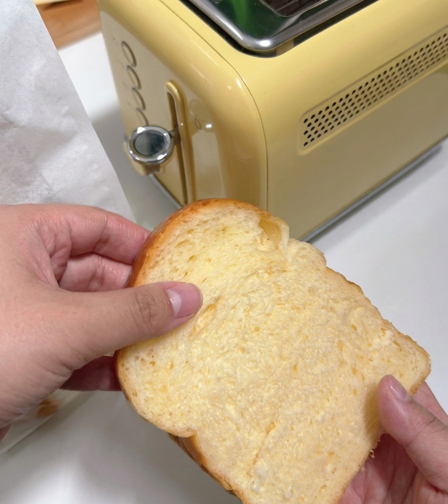 두툼한 식빵을 노란색 토스터기에 넣는 모습.