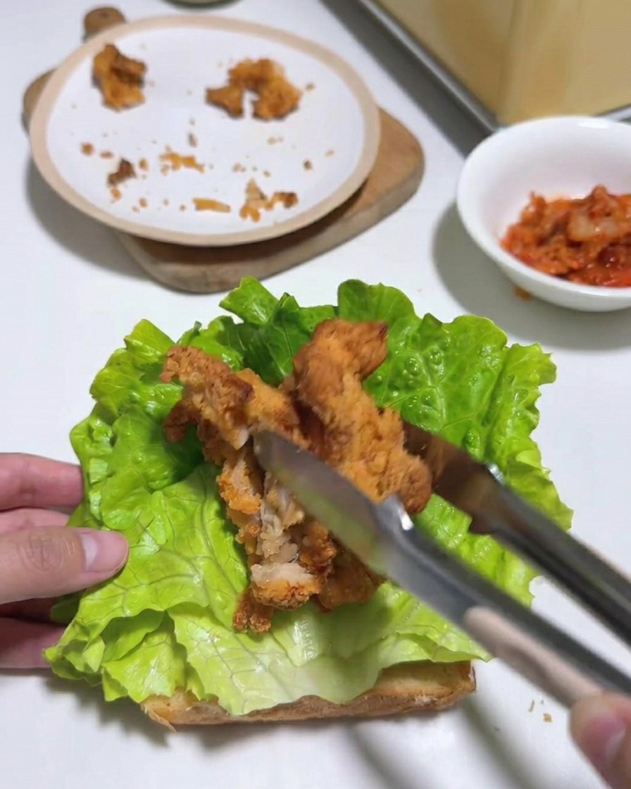 상추 위에 자른 치킨 조각들을 촘촘하게 배치하는 모습.