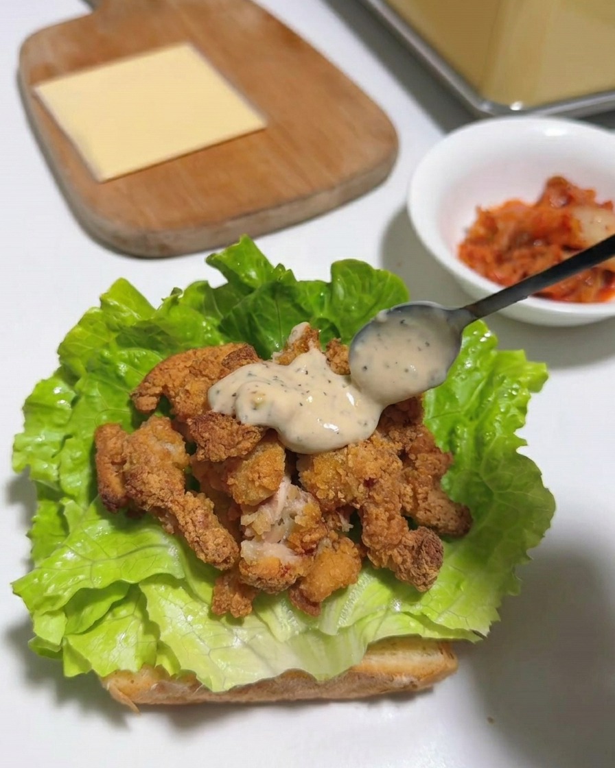 소스가 뿌려진 치킨 위에 노란 치즈 한 장을 올린 모습.