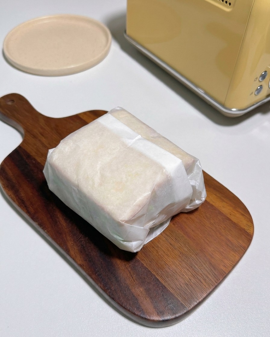 포장된 샌드위치를 반으로 잘라 먹음직스러운 단면을 보여주는 모습.