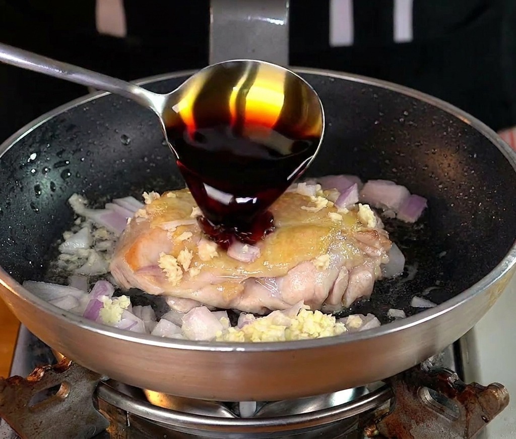 팬 안의 닭다리살 위에 간장을 붓는 모습