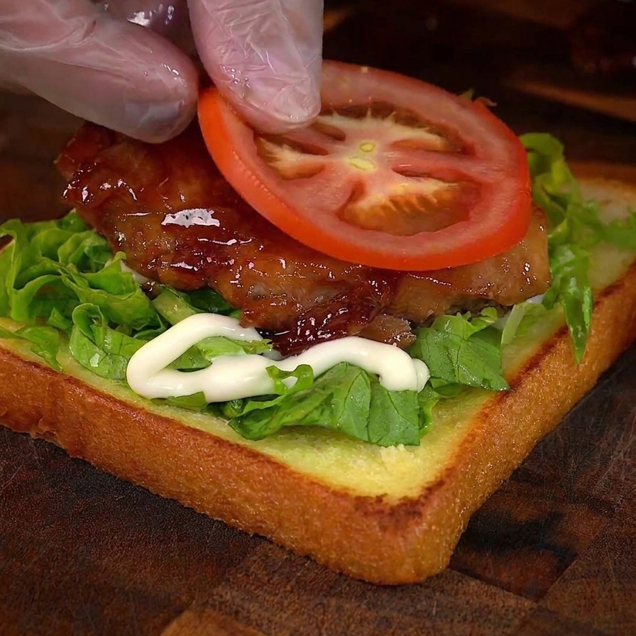 치킨 위에 신선한 토마토 슬라이스를 올리는 모습