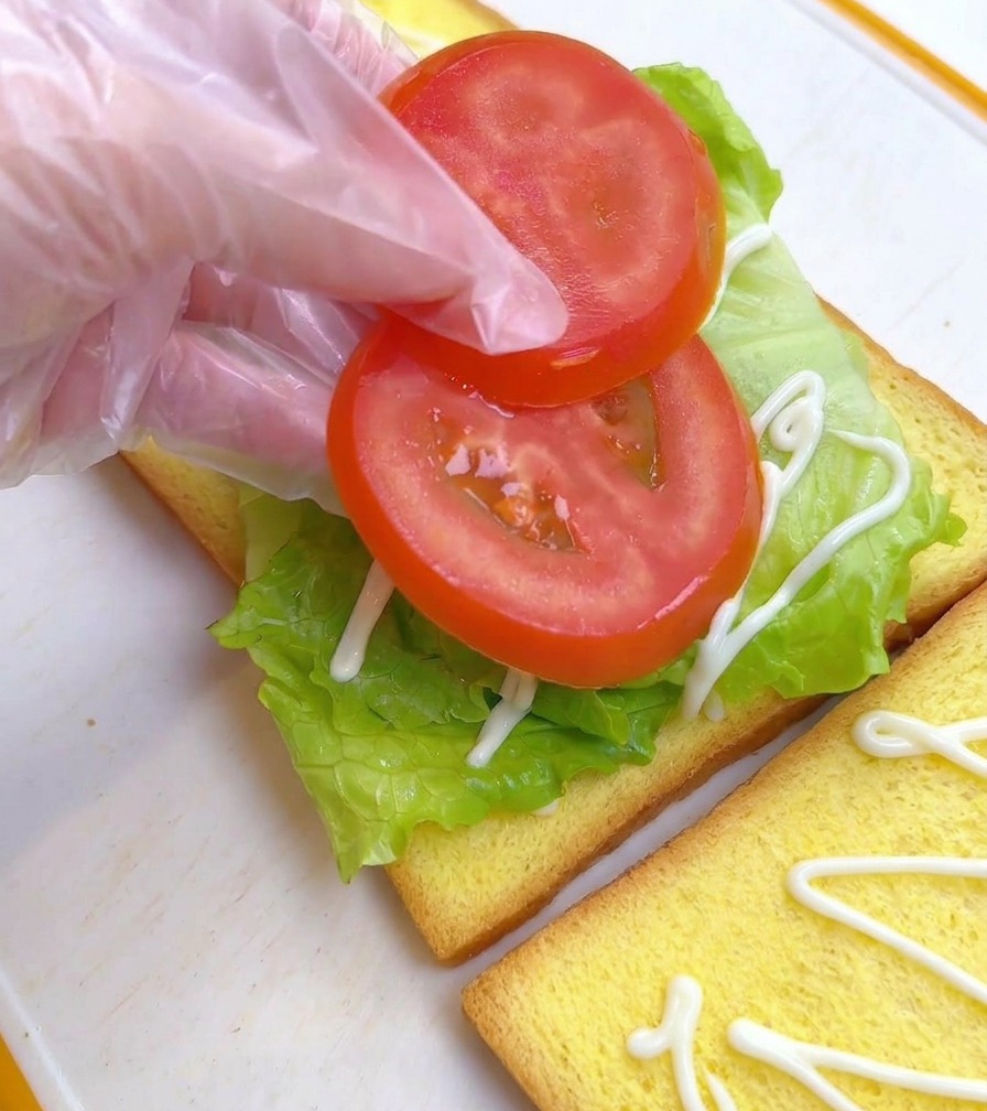 상추 위에 슬라이스한 토마토 두 조각을 올리는 모습.