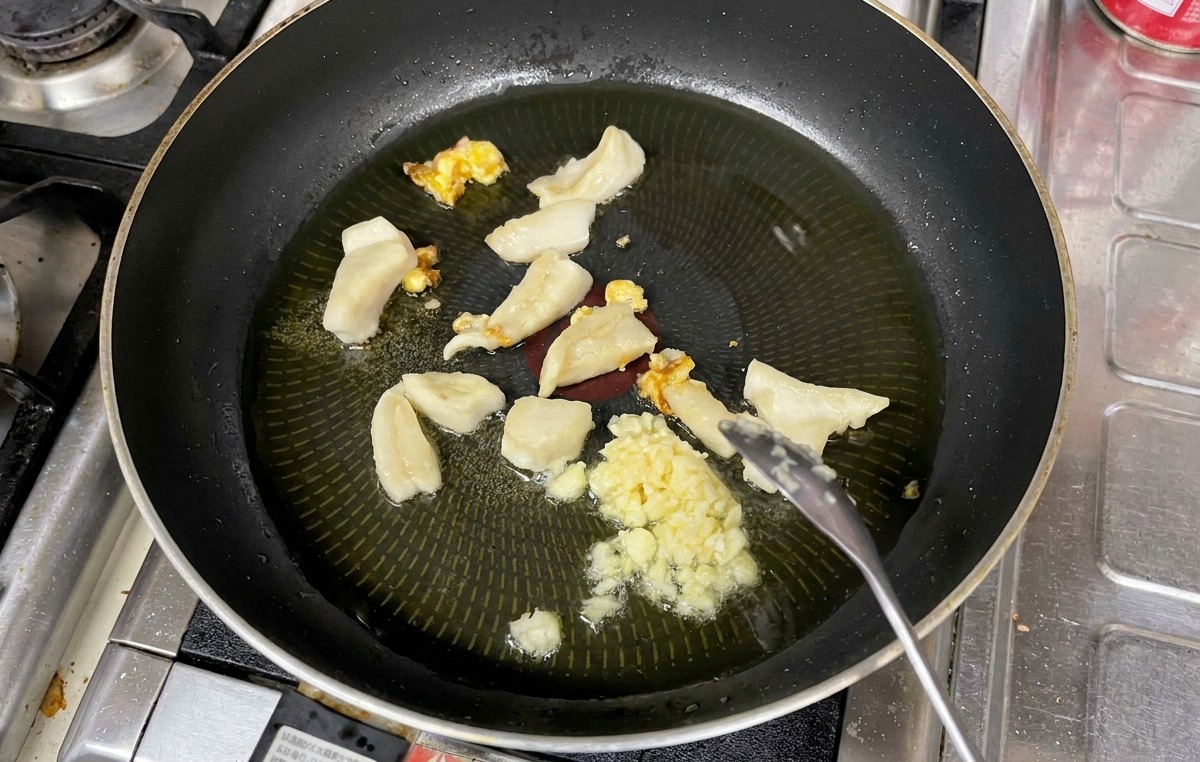 달궈진 기름에 다진 마늘을 넣고 숟가락으로 저으며 볶는 모습
