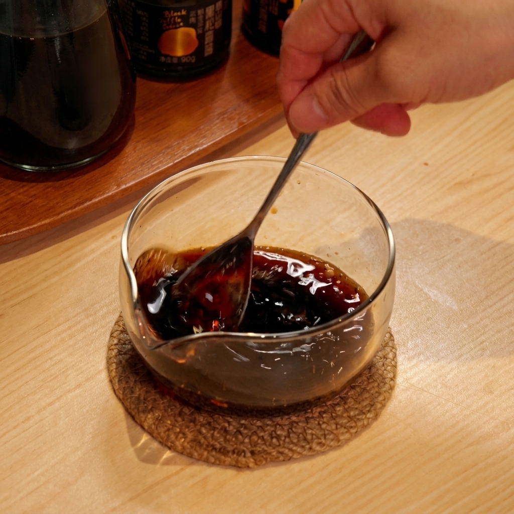 유리 볼에 담긴 진한 소스를 숟가락으로 저어 섞는 모습