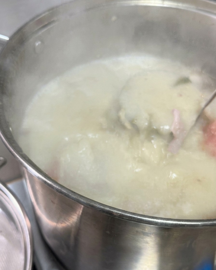 라드와 진한 소스가 담긴 냄비에 메탈 체를 대고 그 위로 뽀얀 돼지 사골 육수를 직접 붓는 모습.